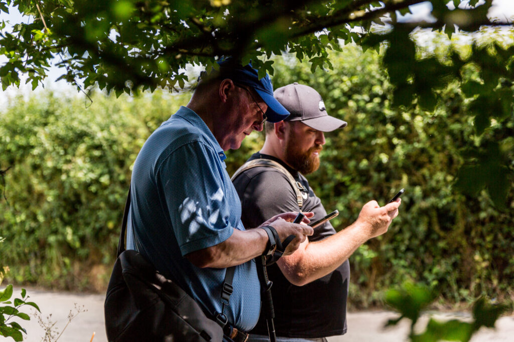 Two men on a walk checking an app on their phones in summer