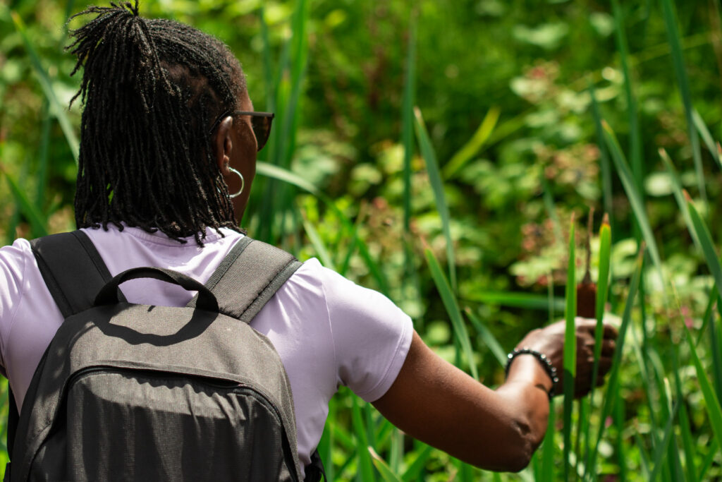 A woman on a walk, pausing to look at plants.