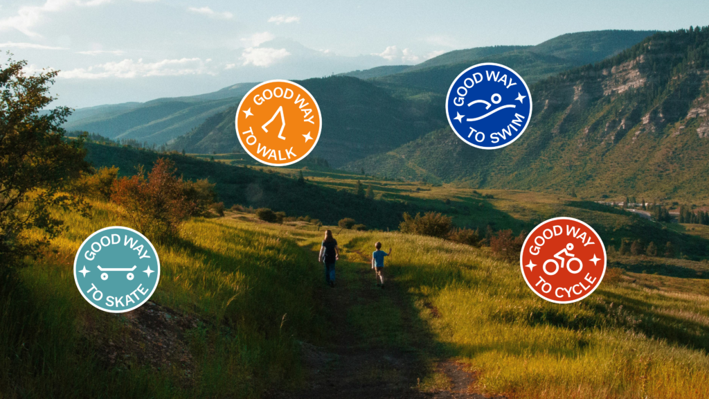 Scenic mountain valley path with two small walkers in the distance. Four round Good Way badges float over the landscape: to walk, to swim, to skate and to cycle.